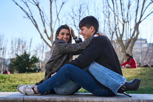 パークのベンチに座って抱きしめ合っている若いカップル愛と関係のコンセプト