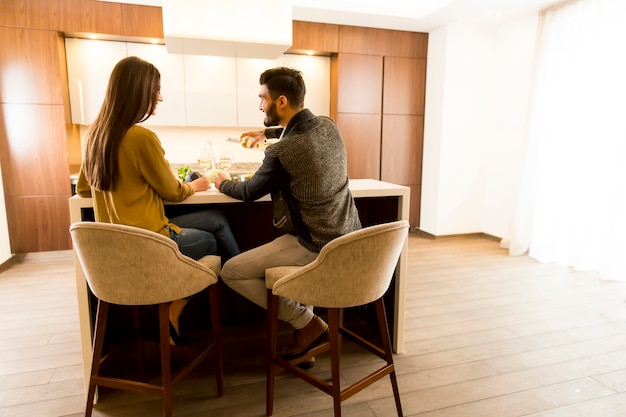 Young couple sitting in the kitchen with his back and drinking white wine