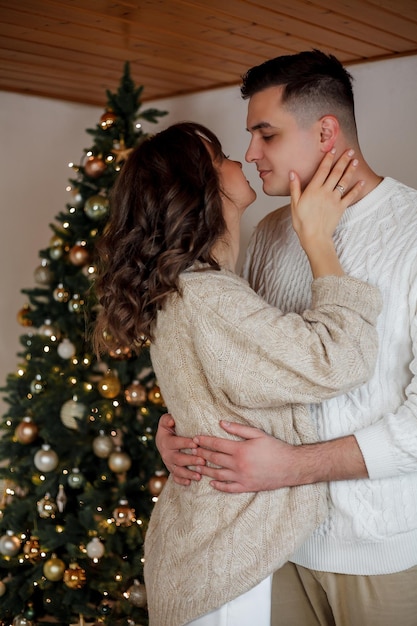 young couple sitting near the christmas tree and opening presents winter holidays