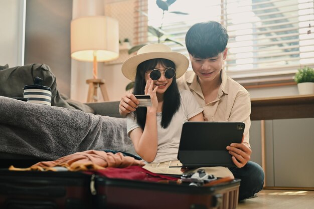 Young couple sitting near suitcases and booking tickets or hotel on web Holiday summer vacation concept