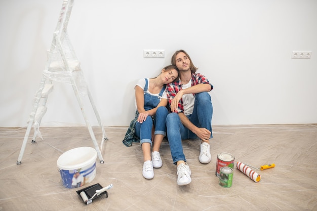 young couple sitting near the wall and feeling tired