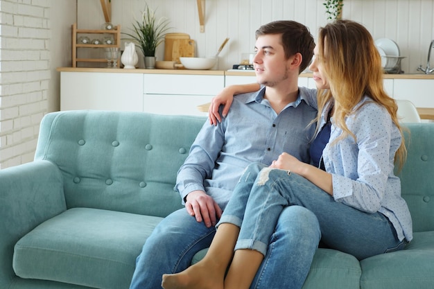 Young couple sitting on sofa and looking away from the camera