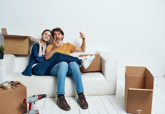 Young couple sitting on white couch boxes moving lifestyle