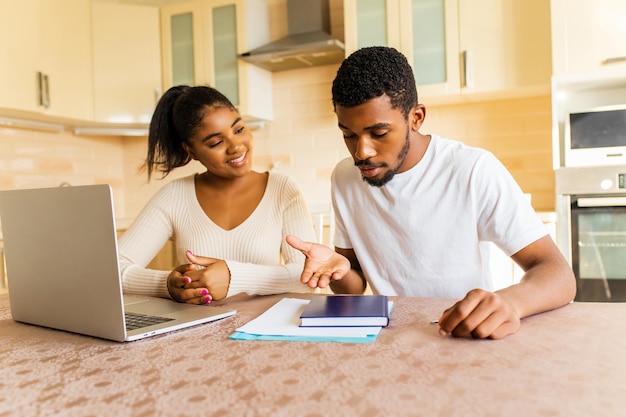 Молодая пара сидит с ноутбуком и учится онлайн на кухне дома