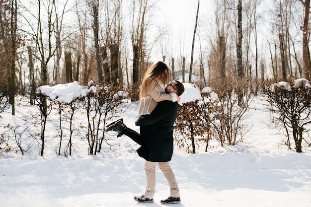 Young couple smile and kissing in the park in winter