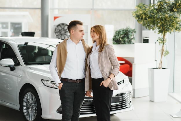 Photo young couple smiling at auto showroom