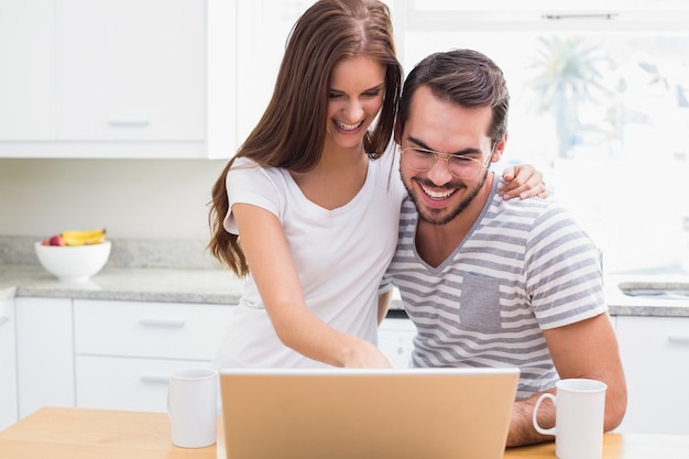 Giovani coppie che sorridono e che per mezzo del computer portatile