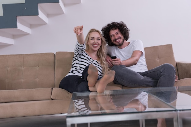 Young couple on the sofa watching television together in their luxury home