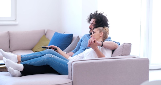 Young couple on the sofa watching television together in their luxury home