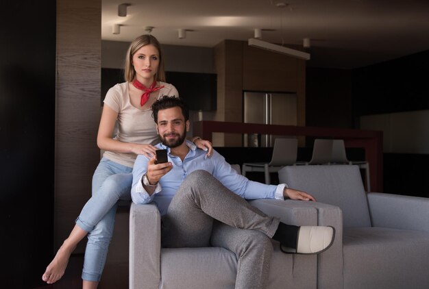 Young couple on the sofa watching television together in their luxury home