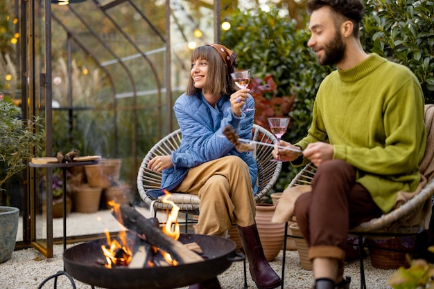 Young couple spending dinner time by the fire at backyard