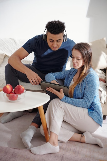 Young couple spending time at home and choosing new movie to watch on digital tablet