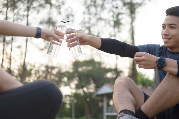 若いカップルスポーツ選手は、トレーニング後の水を飲みます。