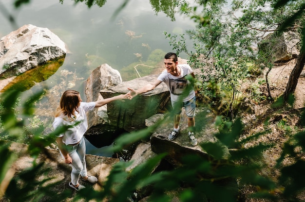 Young couple stand on stone near the lake 