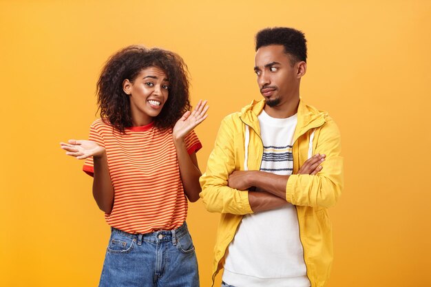 Young couple standing against yellow background