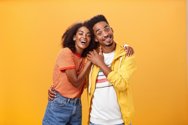 Young couple standing against yellow background