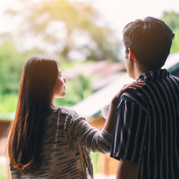 A young couple standing back together