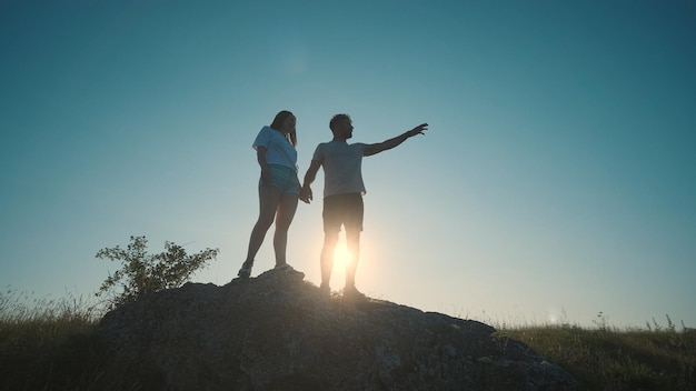 The young couple standing on a mountain top on a blue sky background