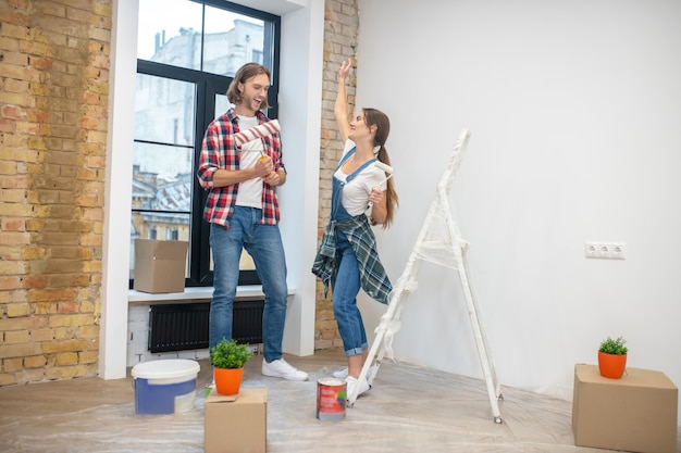 Young couple standing n in the empty room ready to start painting