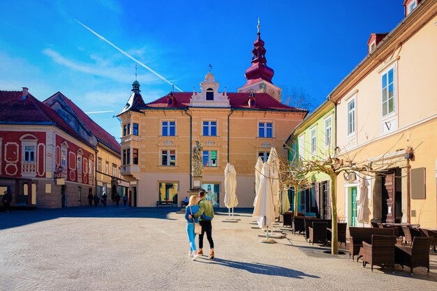 Coppia giovane al caffè di strada con tavoli e sedie nel centro storico di ptuj in slovenia. architettura e ristoranti in slovenia. viaggiare