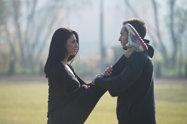 Foto coppia giovane stretching prima di correre in area parco cittadino formazione ed esercizio per trail run marathon endurance fitness stile di vita sano concetto all'aperto