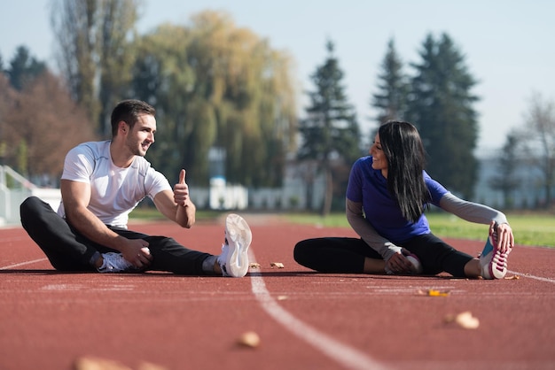 Foto coppia giovane stretching prima di correre in area parco cittadino formazione ed esercizio per trail run marathon endurance fitness stile di vita sano concetto all'aperto