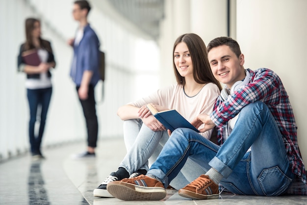 Young couple students sitting in corridor in college.