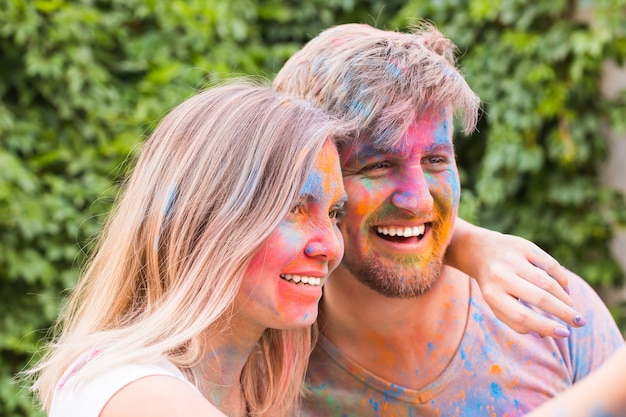 Young couple taking selfie in colourful dirty clothes