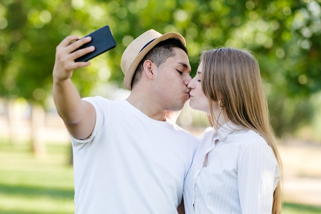 공원에서 자신의 모바일에 selfie를 복용하는 젊은 부부