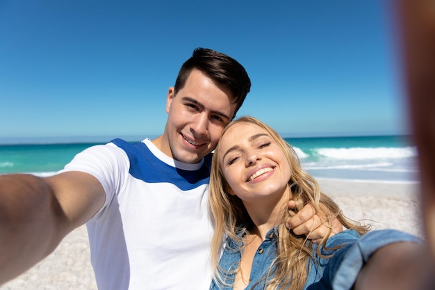 Young couple taking selfies at the beach