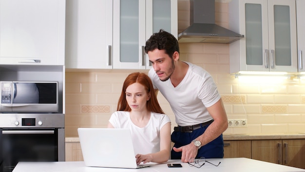 young couple talking and using tablet in kitchen at home