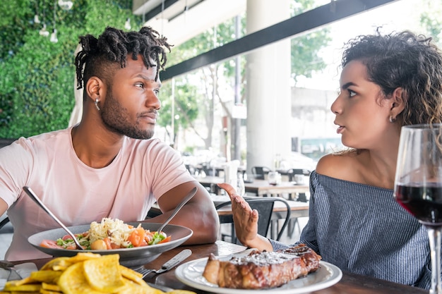 Young couple talking while having lunch together at a restaurant. Relationship concept.