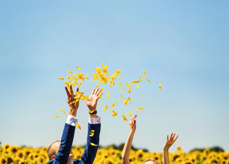 Photo フィールドにひまわりの花びらを投げる若いカップル