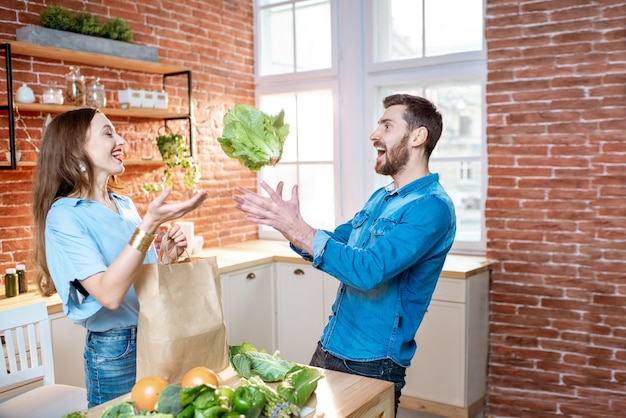 Foto giovane coppia che lancia con una testa di cavolo fresco che si prepara a cucinare pasti vegani in cucina a casa