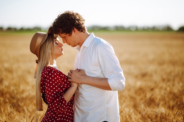 Young couple together in the wheat field during summer