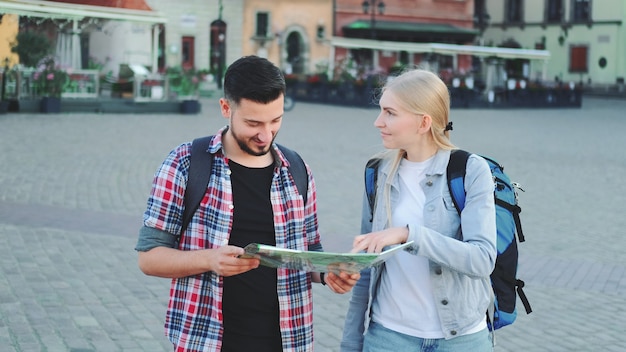 Young couple of tourists with map looking for new historical place in city center