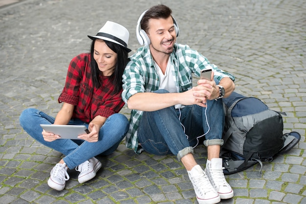 Photo young couple tourists with a tablet and headphones in city.