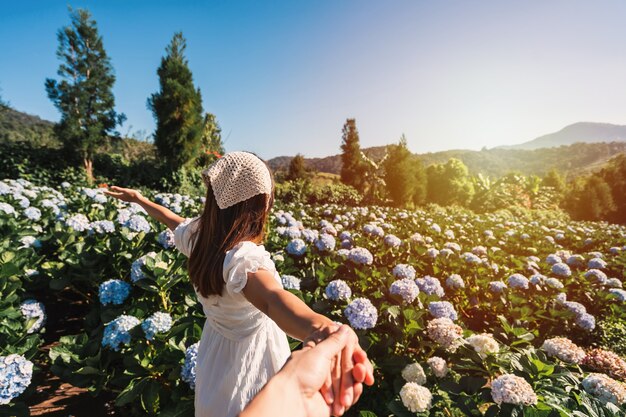 Young couple traveler relaxing and enjoying with blooming hydrangeas flower field