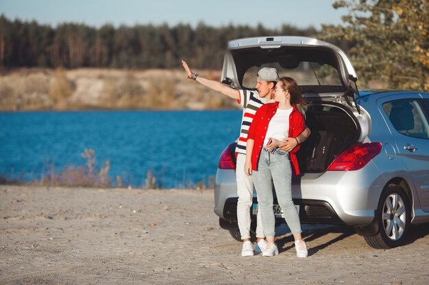 車で旅行する若いカップル。女と男の自動車旅行。屋外の幸せな若者。