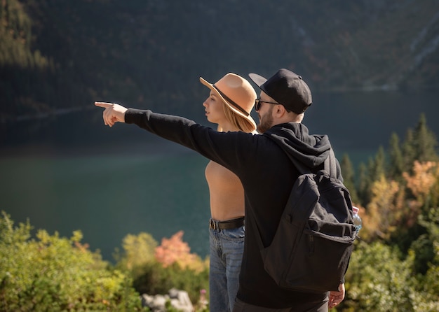 山を旅する若いカップル。男は自然の背景を持つ山で指摘しています