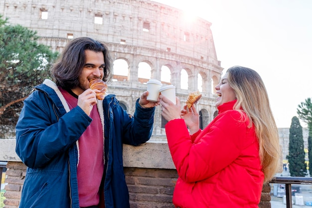 사진 로마를 여행하는 젊은 부부는 크로아산을 먹고 커피를 마시고 있습니다.