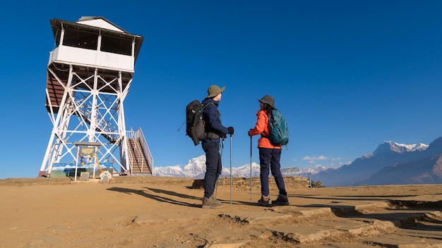 A young couple travellers trekking in Poon Hill view point in Ghorepani Nepal