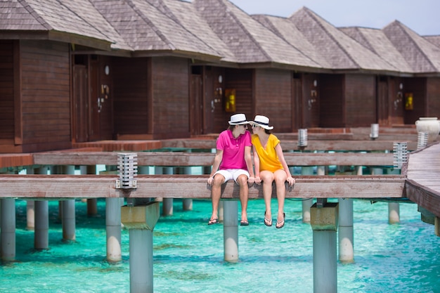 Young couple on tropical beach jetty near water bungalow