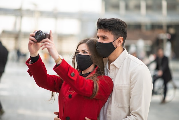 Young couple of turists taking pictures in a city during covid or coronavirus pandemic