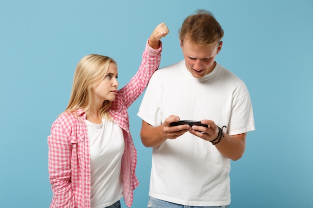 Young couple two friends man and woman  in white pink empty t-shirts posing 