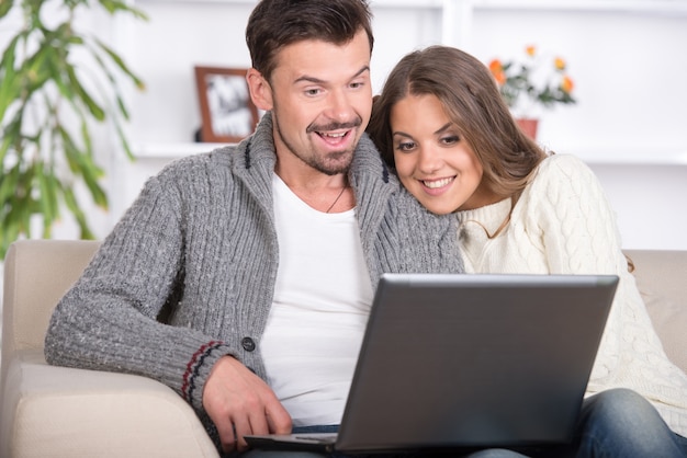 Молодая пара, используя портативный компьютер у себя дома.