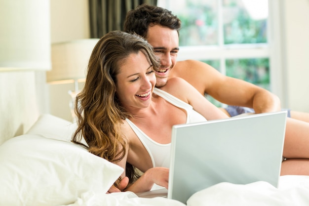 Young couple using laptop on bed in bedroom