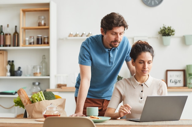 Молодая пара, используя портативный компьютер дома, они заказывают продукты онлайн
