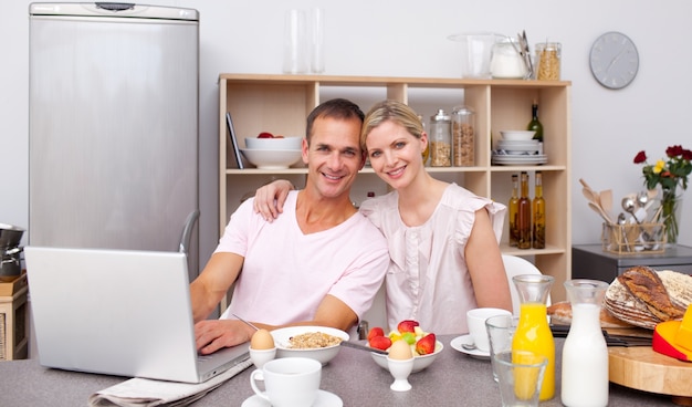 Young couple using a laptop while having breakfast 