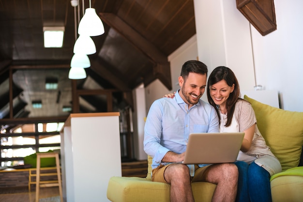 Young couple using a laptop while sitting on a sofa